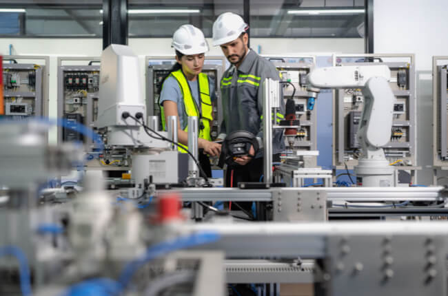 Engineers examining automated production line in factory setting